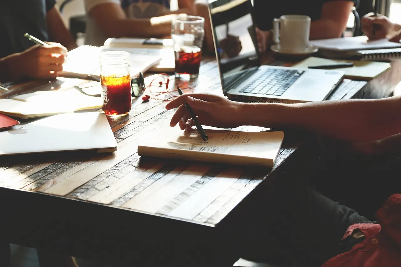 A team working around a table with laptops, notebooks and cups