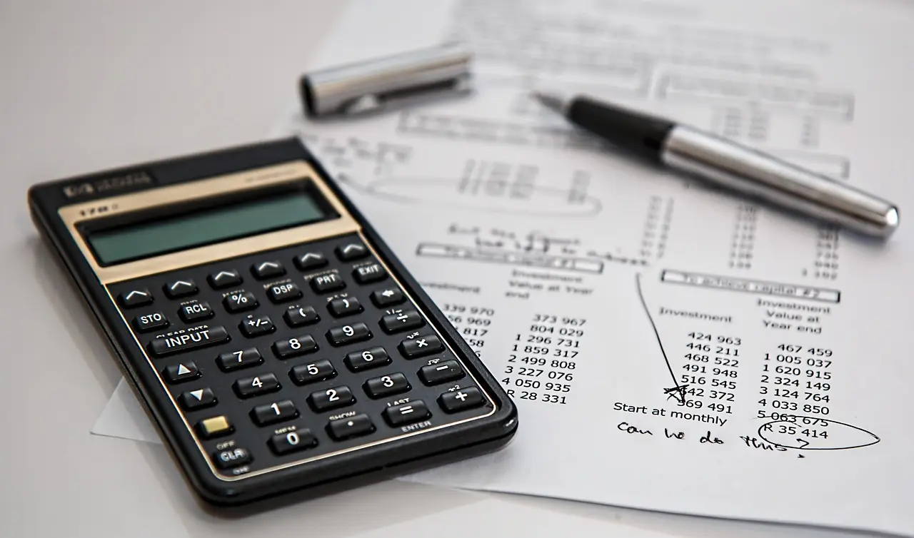 Calculatrice et stylo plume posés sur un document de comptabilité financière